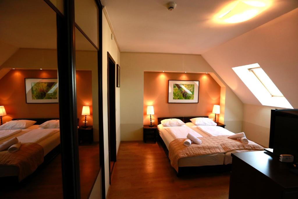a hotel room with two beds and a mirror at Fürjes Villa Panzió in Balatonfüred