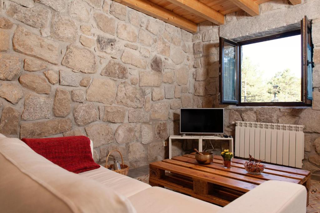 sala de estar con pared de piedra en Huerto San Antonio, en La Cabrera