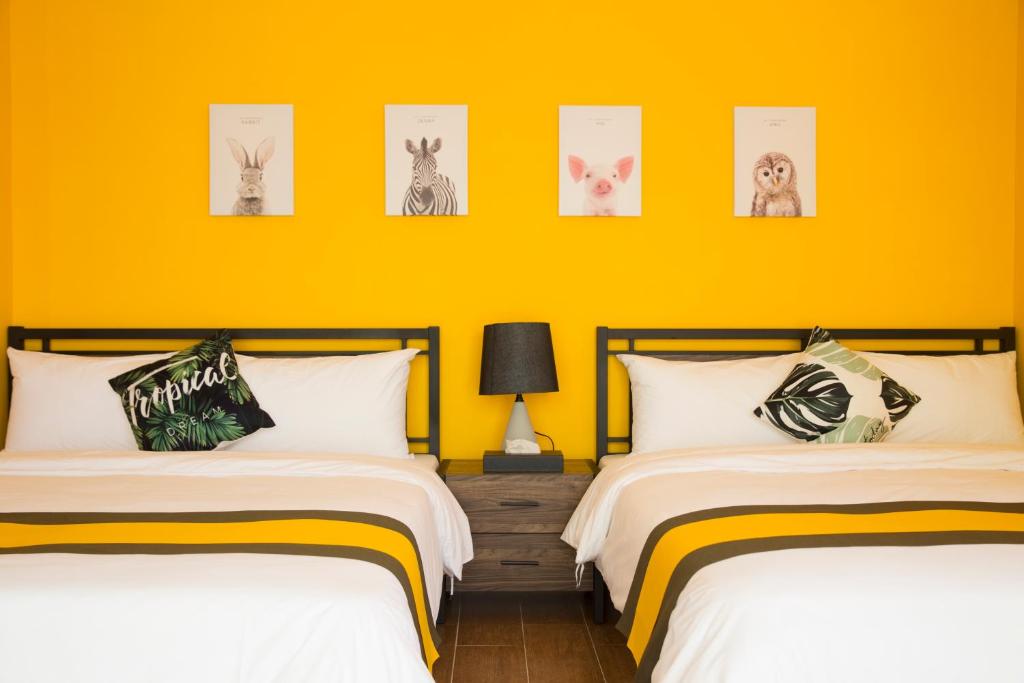 2 łóżka w pokoju z żółtymi ścianami w obiekcie 綠光海岸民宿 w mieście Magong