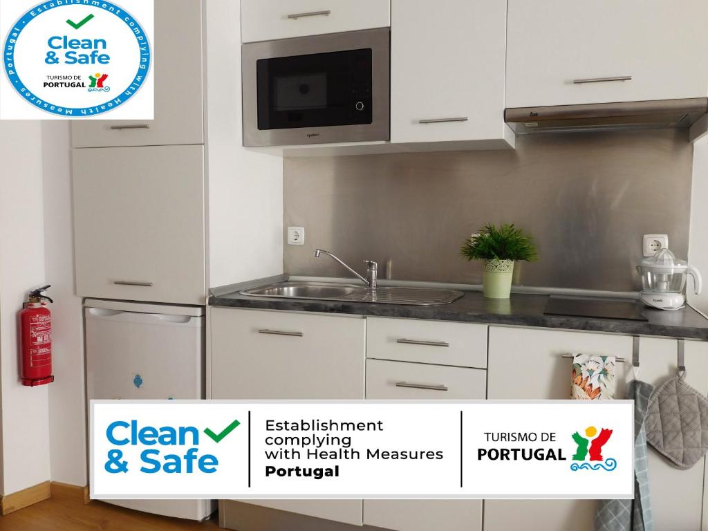 a kitchen with white cabinets and a sink and a sign at Alfama T1 Travel in Lisbon