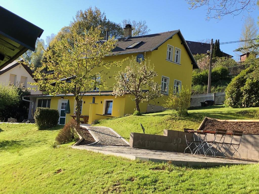 ein gelbes Haus auf einem üppigen grünen Hof in der Unterkunft Ferienhaus Sandy in Bad Elster