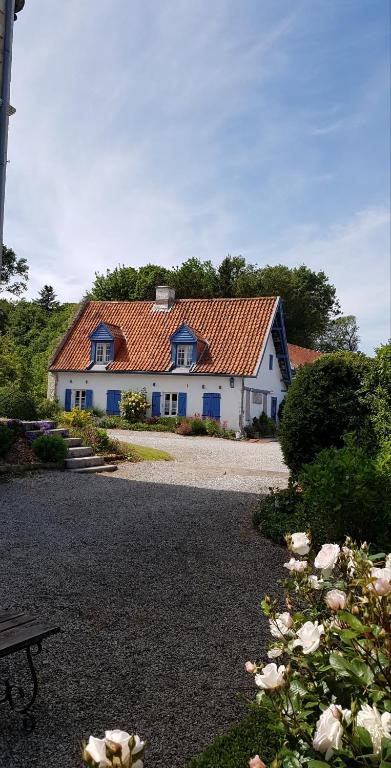 une grande maison blanche avec un toit orange dans l'établissement B&B au petit tambour d'Autingues, à Autingues