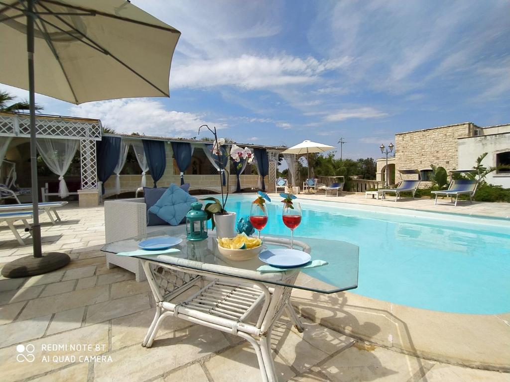 una mesa con copas de vino junto a la piscina en B&B Tenuta Martinelli, en Monopoli