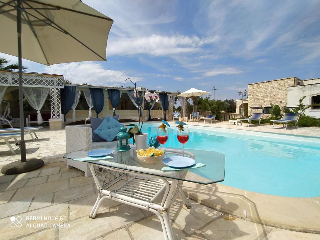 a table with wine glasses next to a swimming pool at B&B Tenuta Martinelli in Monopoli