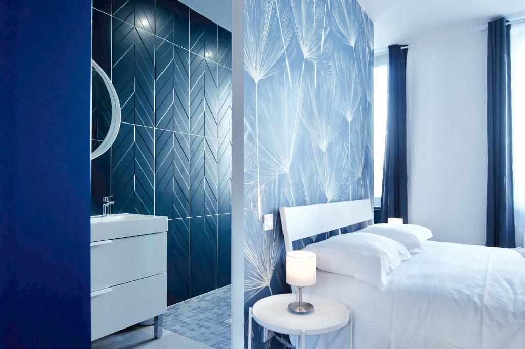 1 dormitorio con cama blanca y pared azul en NuitéeJour Niort Centre, en Niort