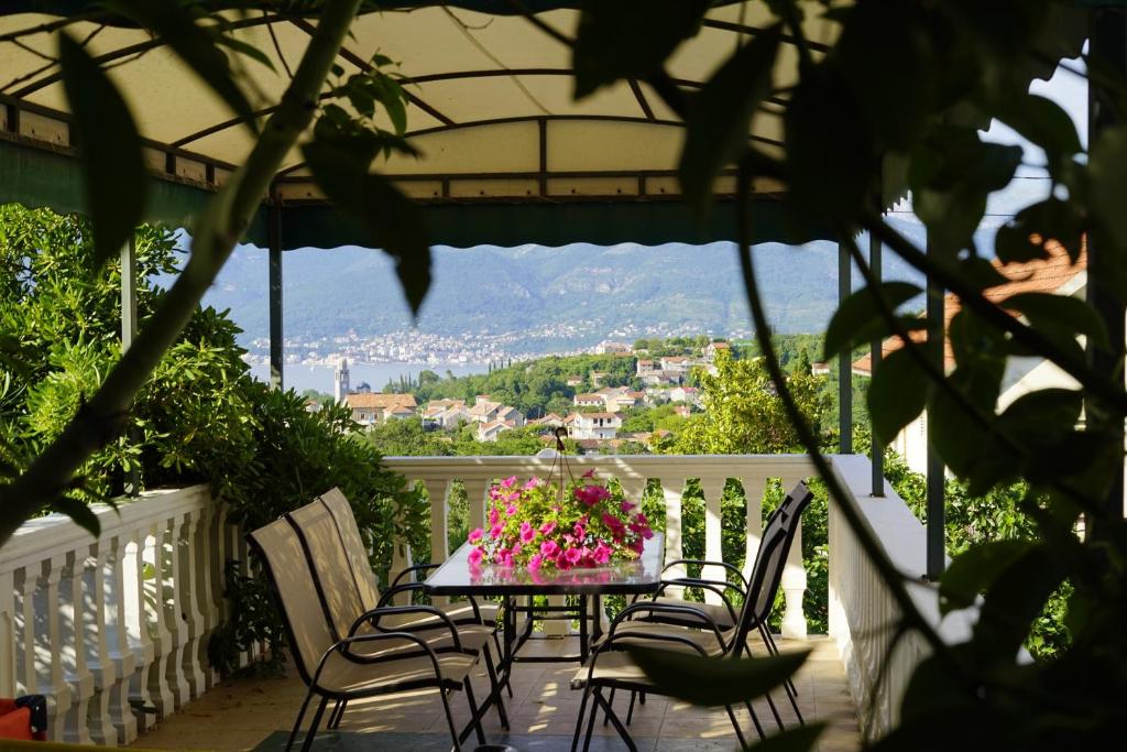 einen Tisch mit Stühlen und Blumen auf dem Balkon in der Unterkunft 2 bedrooms appartement at Radovici 900 m away from the beach with furnished balcony and wifi in Tivat