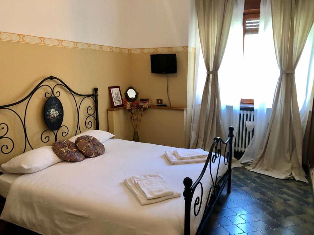 um quarto com uma cama grande com lençóis brancos e almofadas em Appartamenti La Menaresta em Magreglio