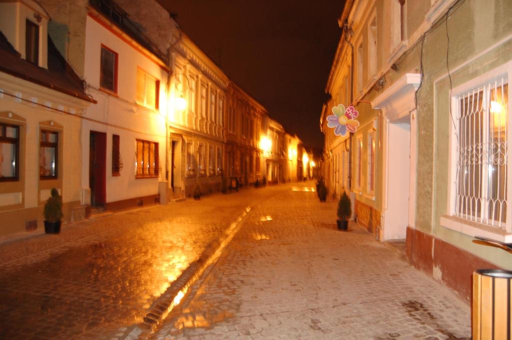 una calle de ciudad vacía por la noche con luces en Casa Piata Sfatului, en Brasov