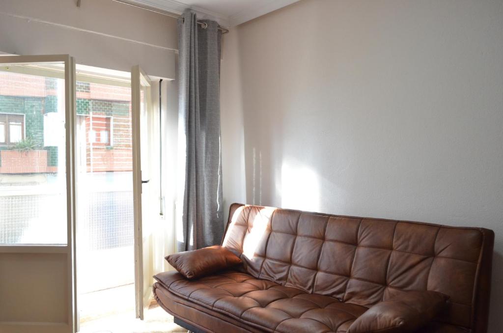 a brown leather couch in a room with a window at El mirador de Noemí in Gijón