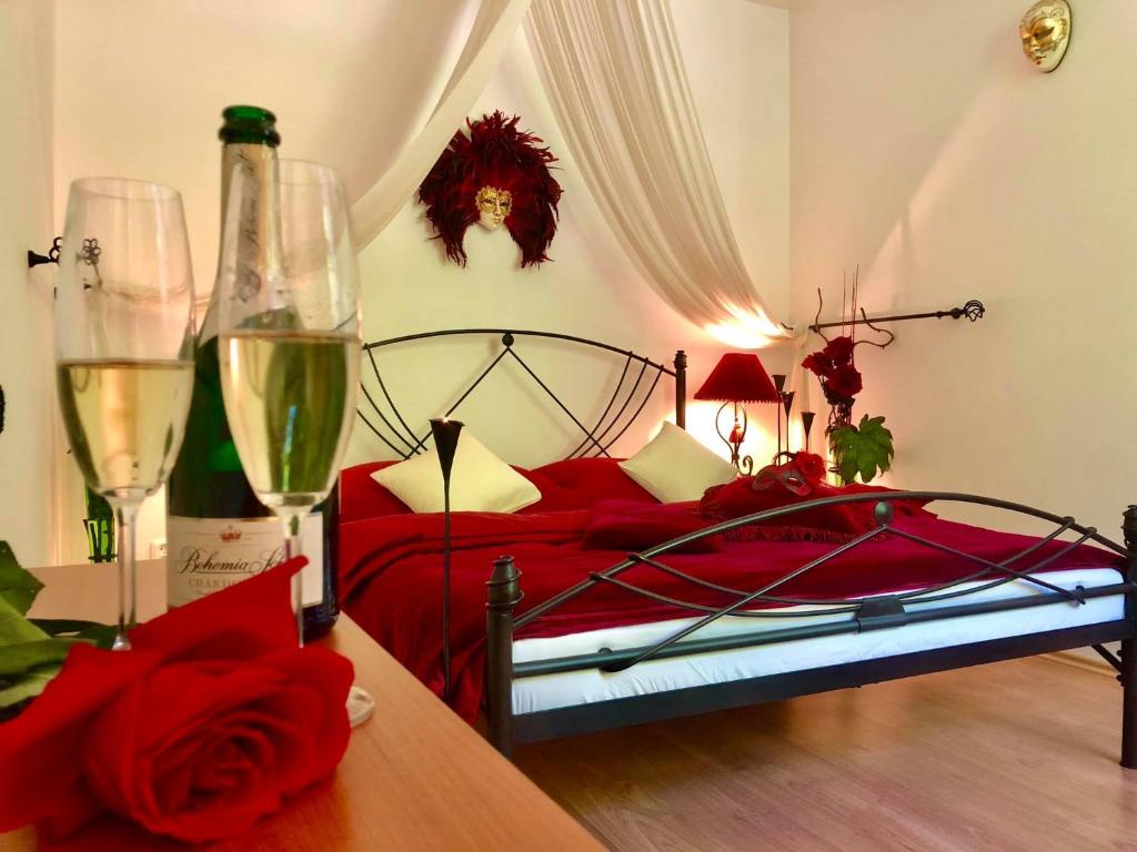 a bedroom with a bed and two glasses of wine at Apartmány Kolonáda in Luhačovice