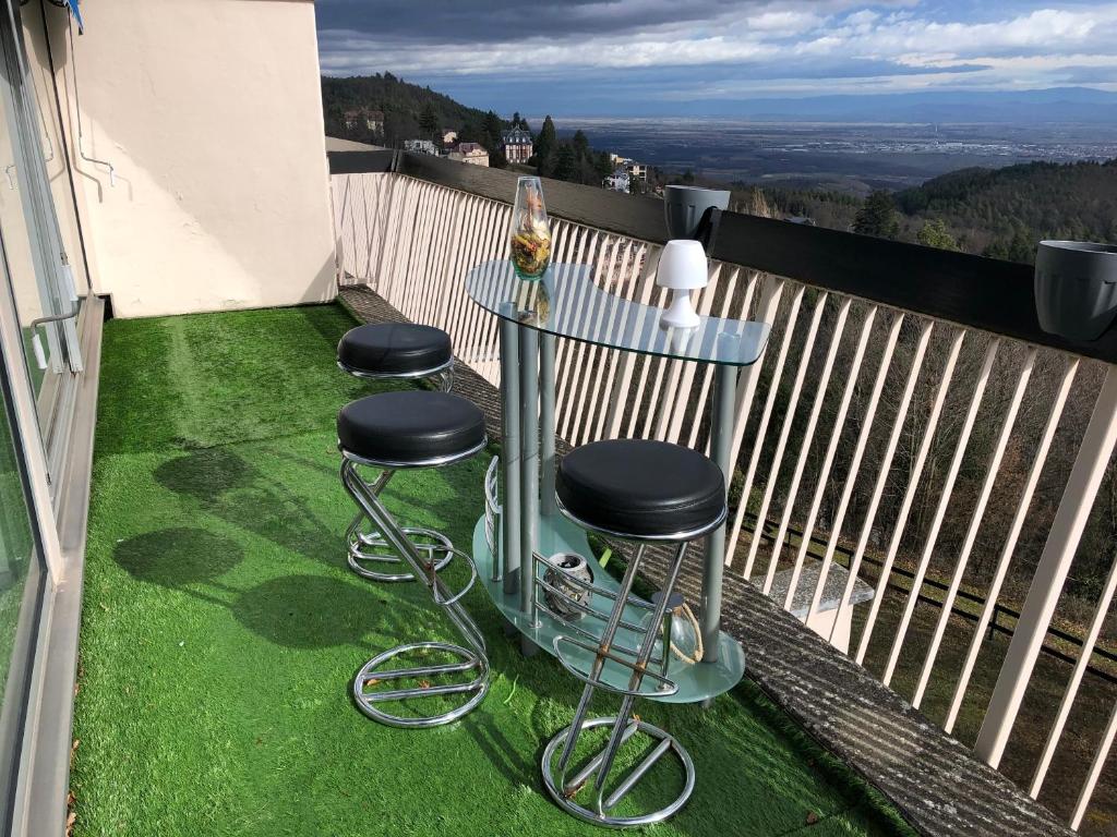 a table and stools on a balcony with green grass at Petit moment de Bonheur in Turckheim