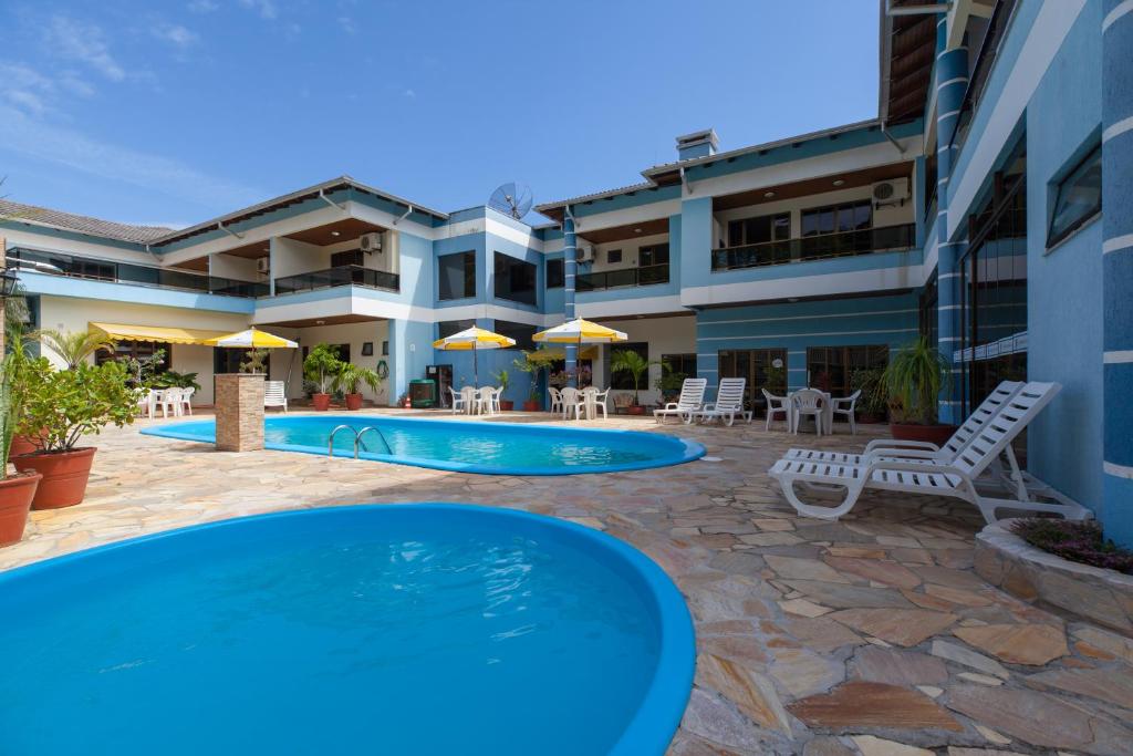 - une piscine avec des chaises et des parasols en face d'un bâtiment dans l'établissement Refúgio Costeiro II, à Bombinhas