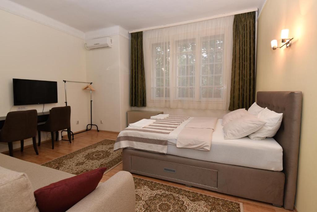 um quarto com uma cama, uma secretária e uma televisão em Apartment Nikola em Belgrado