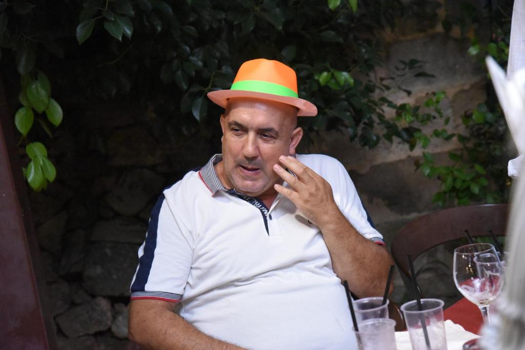 un hombre con un sombrero naranja y verde sentado en una mesa en Villa Vasagè, en Torre Squillace