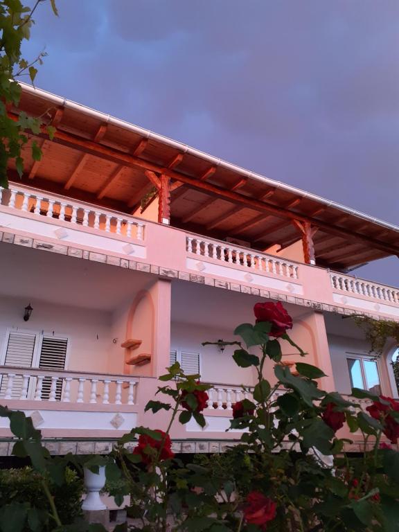 una casa blanca con rosas rojas delante de ella en Apartments Balen, en Rab