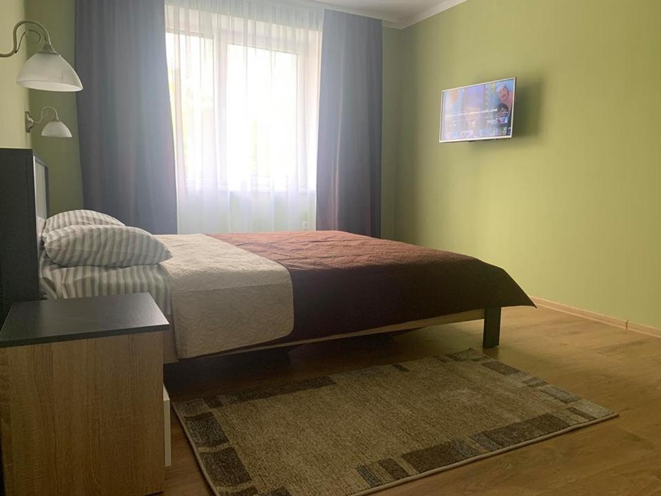 1 dormitorio con 1 cama con ventana y alfombra en Апартаменти Monte, en Rakhiv