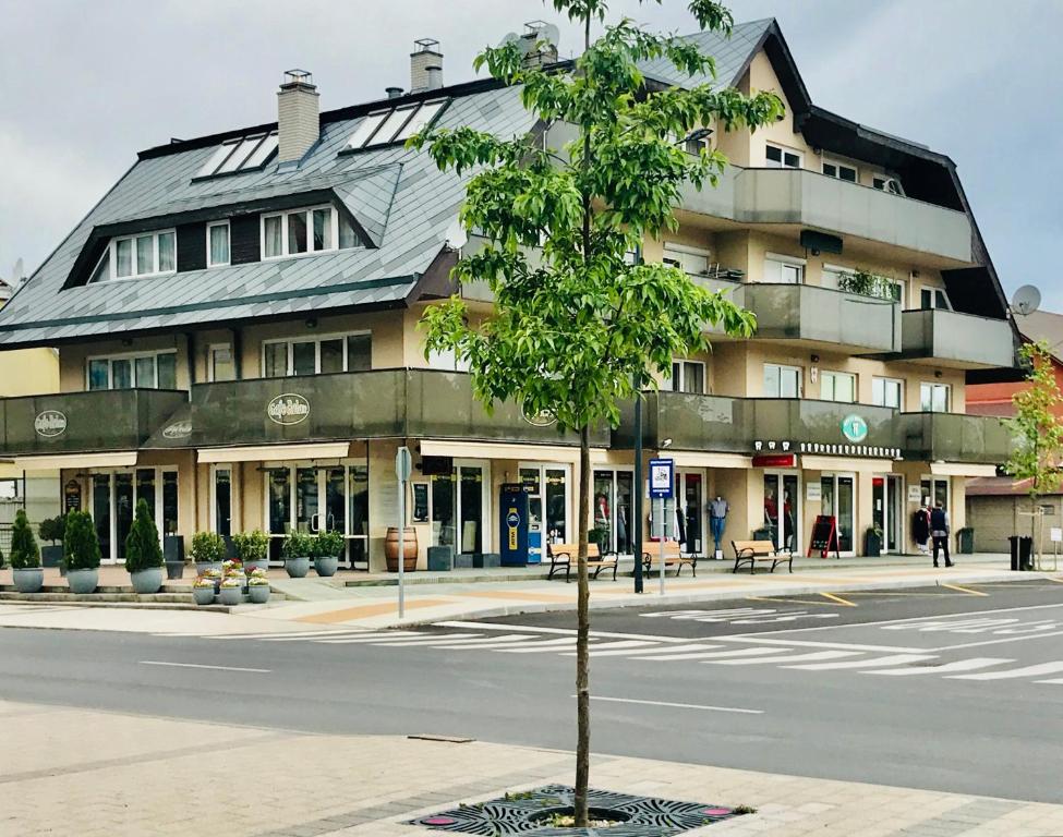 uma árvore em frente a um edifício numa rua em Cafe Relax Apartments em Hévíz