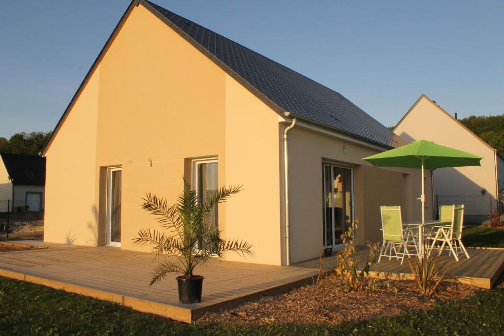 une maison avec une terrasse et un parasol vert dans l'établissement La Goulette du Vary, à Commes