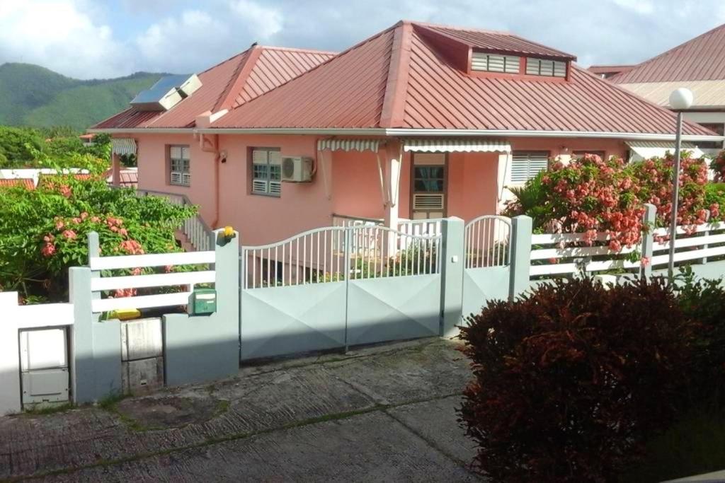 a white fence in front of a pink house at Appartement cosy avec vue sur le jardin à Sainte Anne, 30 m² in Sainte-Anne