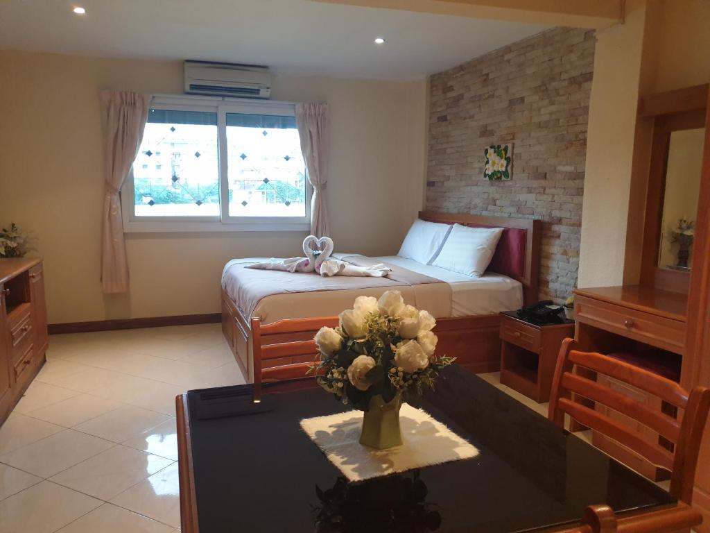 a bedroom with a bed and a table with a vase of flowers at Chaiyapoon Inn in Pattaya Central