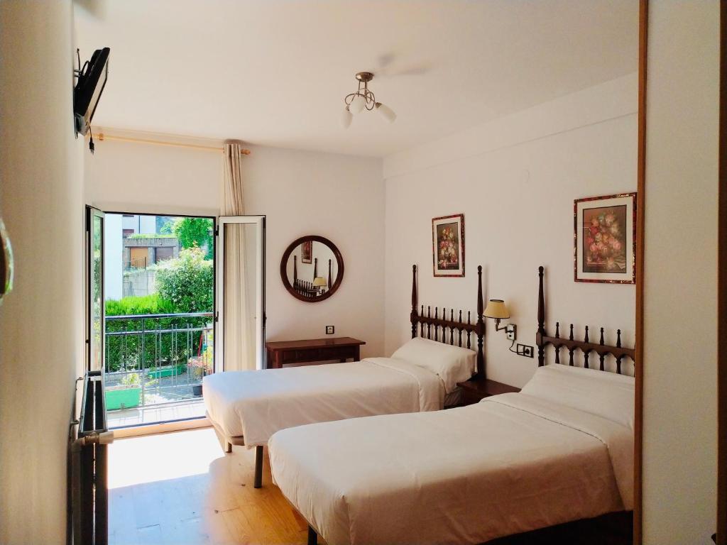 dwa łóżka w pokoju z oknem w obiekcie Hostal Pirineos Meliz w mieście Bielsa