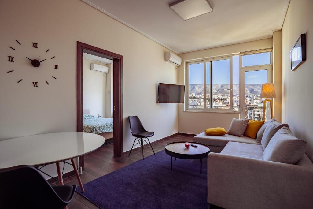 a living room with a couch and a table and a clock at Acropolis comfy home in the heart of Athens for 4 in Athens