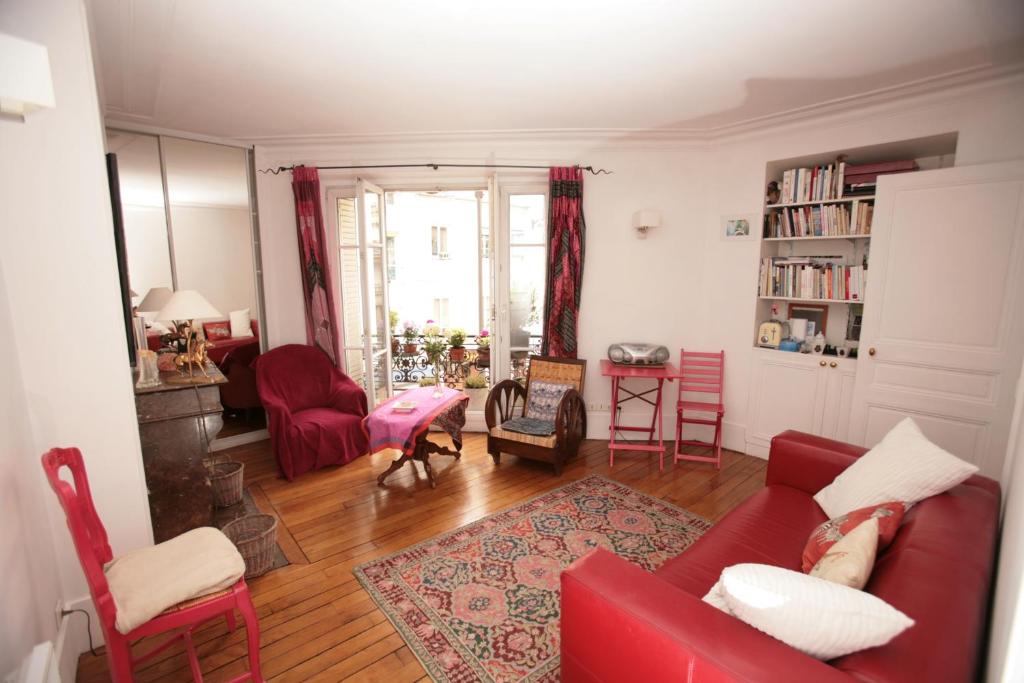 uma sala de estar com um sofá vermelho e cadeiras em Appartement Opéra Paris em Paris