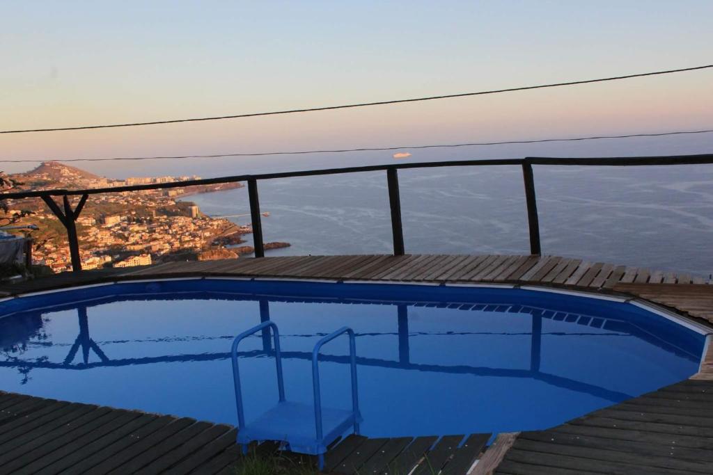 a blue swimming pool with a view of the city at Quarto vista mar in Câmara de Lobos