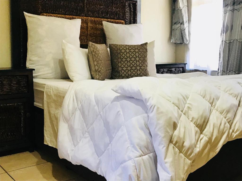 a bedroom with a large bed with white sheets and pillows at Kaste Guesthouse Secunda in Secunda