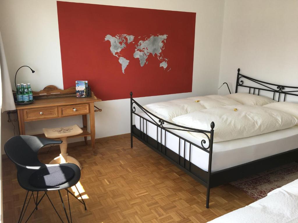 a bedroom with a bed and a desk and a world map on the wall at Lakelodge-Romanshorn 2 in Romanshorn