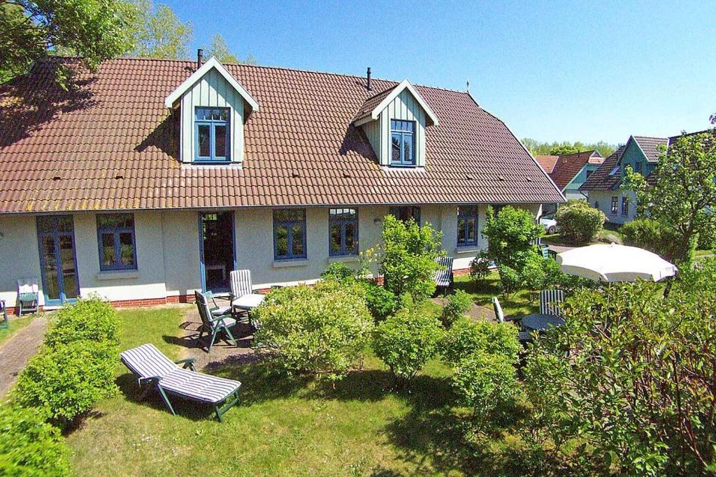 une maison avec une cour dotée d'un banc et d'un parasol dans l'établissement Ferienhaussiedlung Strandperlen Weidenhof 8b (Typ V), à Wustrow