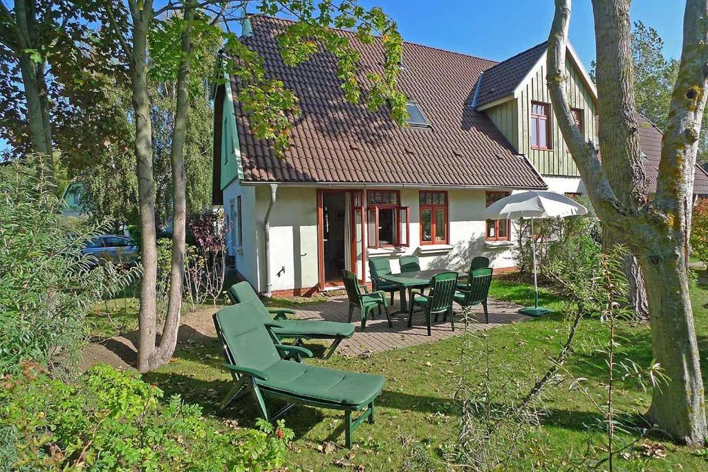 een huis met stoelen en tafels in de tuin bij Ferienhaussiedlung Strandperlen Sanddornhof 2a (Typ VIII) in Wustrow