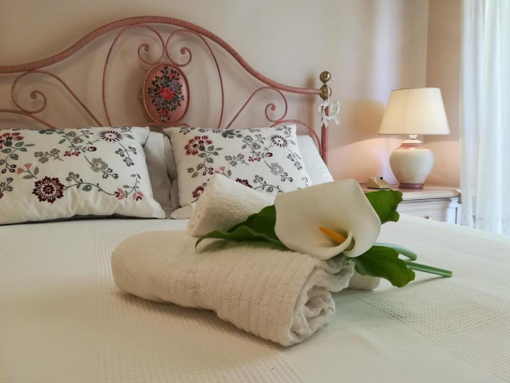 uma toalha numa cama com almofadas e uma flor em A CASA DI TATI em Civitanova Marche
