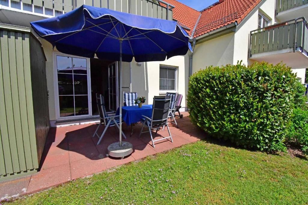 een blauwe parasol op een patio met stoelen en een tafel bij ALTES WASSERWERK Whg. AW-07 in Wustrow
