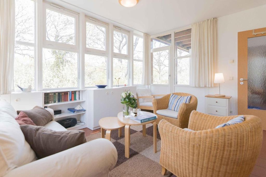 uma sala de estar com um sofá, cadeiras e janelas em Haus LONGARD em Ahrenshoop