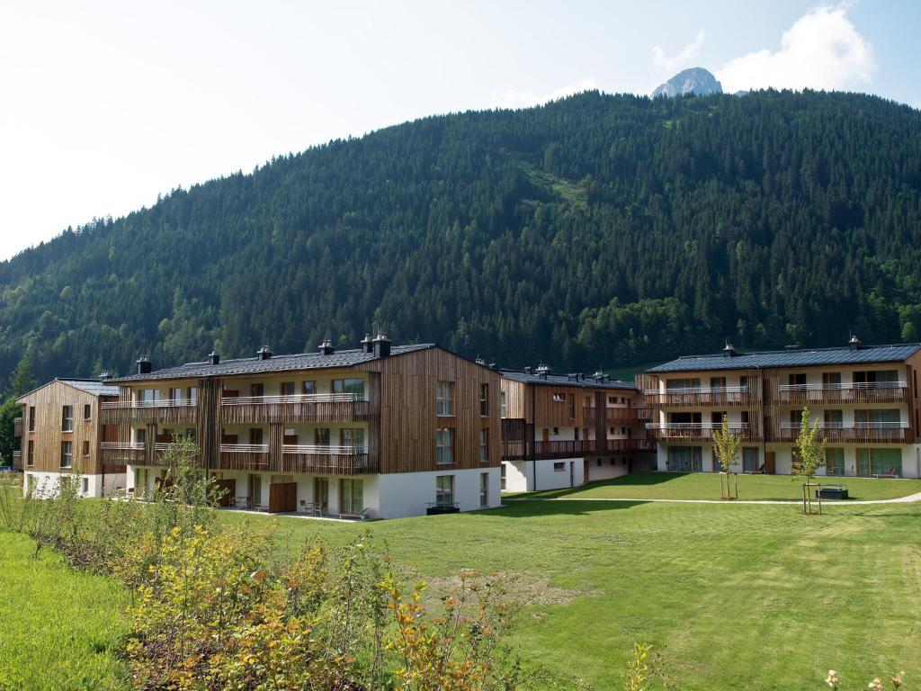 a large building with a mountain in the background at Ferienwohnungen am Travel Charme Bergresort Werfenweng in Werfenweng