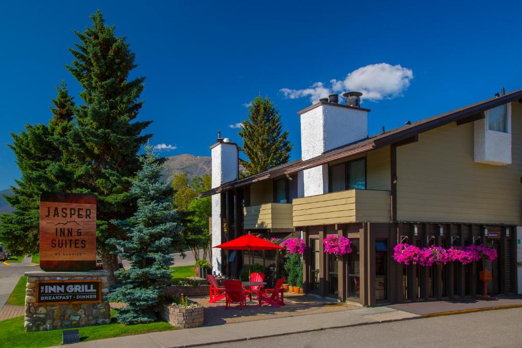 a inn with pink tables and chairs in front of a building at Jasper Inn & Suites by INNhotels in Jasper