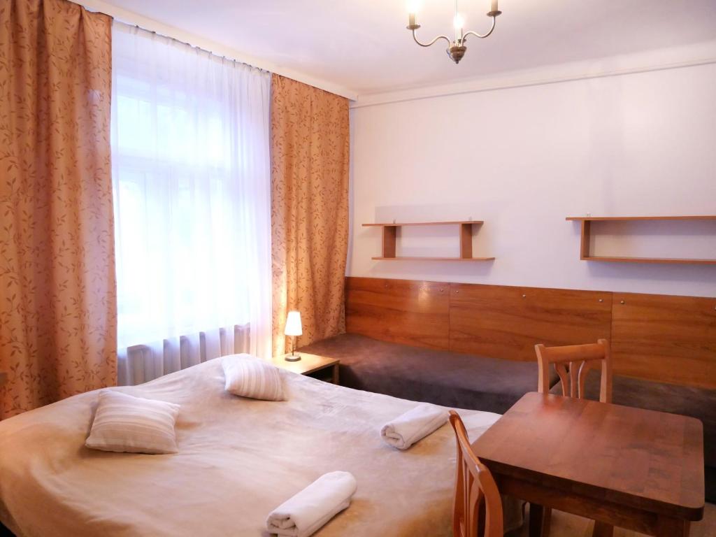 a bedroom with a bed and a table and a window at Pokoje Szczawnica Centrum - duży ogród in Szczawnica
