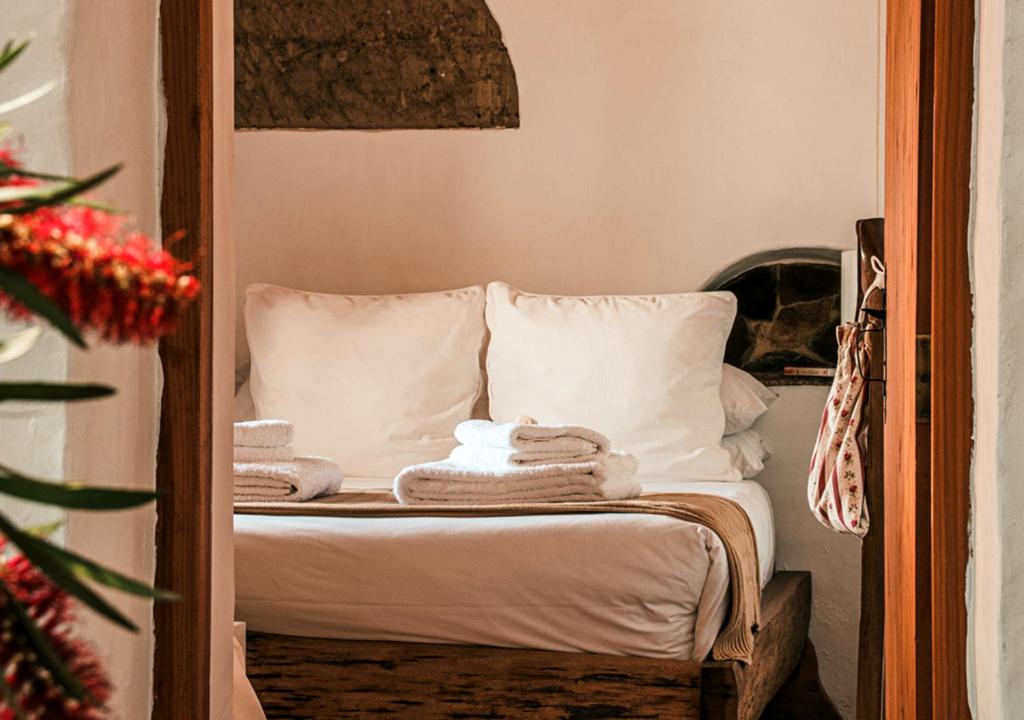 a bedroom with a bed with white sheets and pillows at Cerro Da Fontinha in São Teotónio