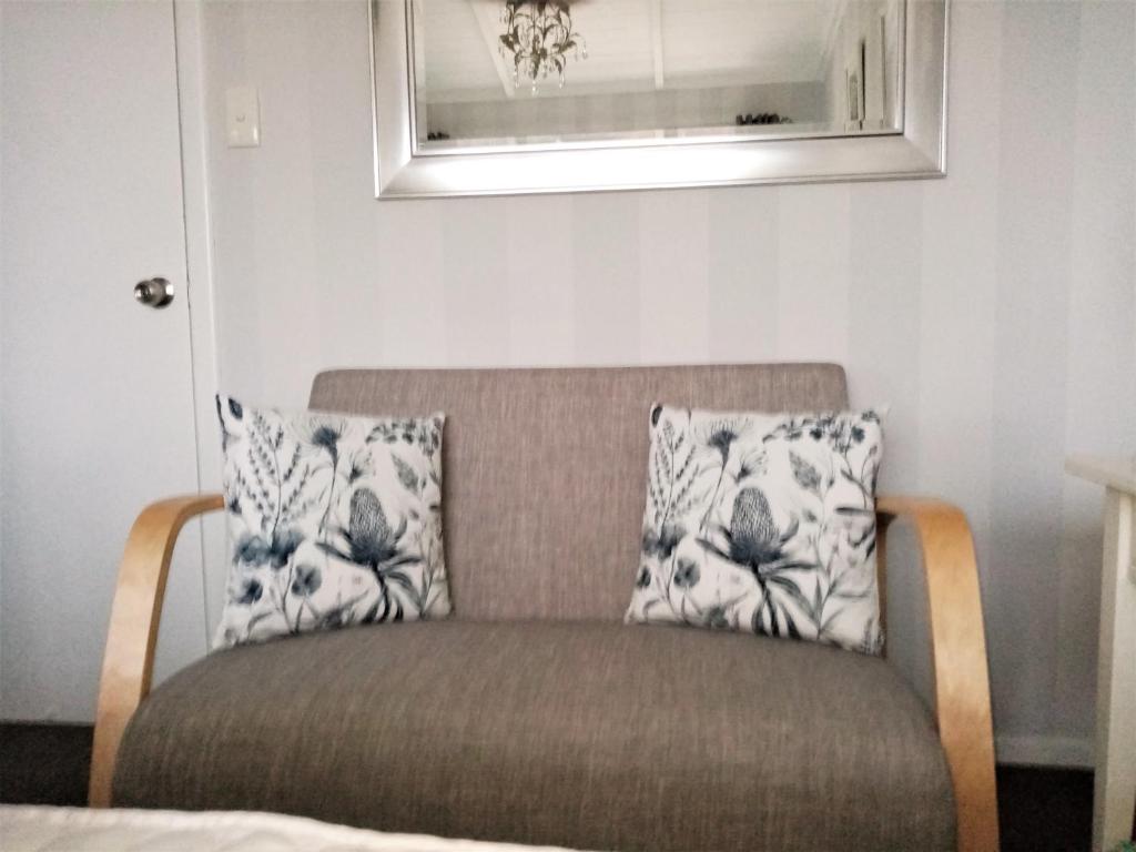 a couch with two pillows on it in a room at 66 Chaucer B&B with Complimentary Breakfast to Go Bag in Cambridge