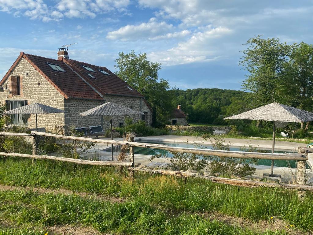 a house with a pool and umbrellas in front of it at Domaine de Combraille en Marche in Saint-Médard