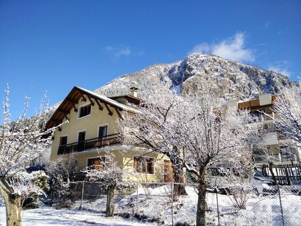 une maison en face d'une montagne enneigée dans l'établissement Chalet de 7 chambres avec sauna jardin et wifi a Briancon a 1 km des pistes, à Briançon