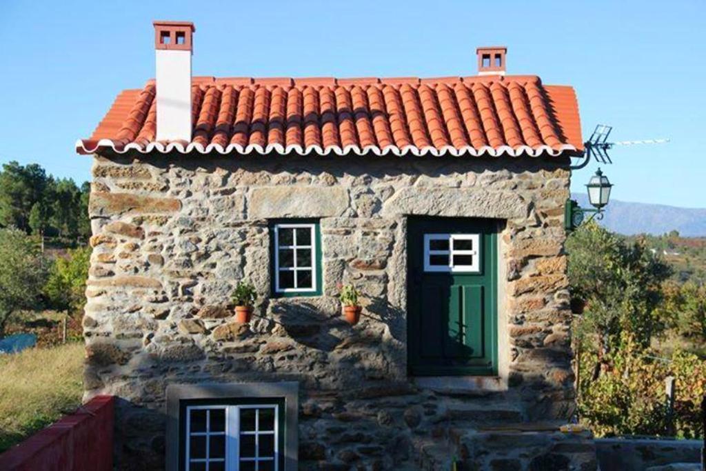une petite maison en pierre avec une porte verte dans l'établissement One bedroom house with enclosed garden at Souto da Casa, à Souto da Casa