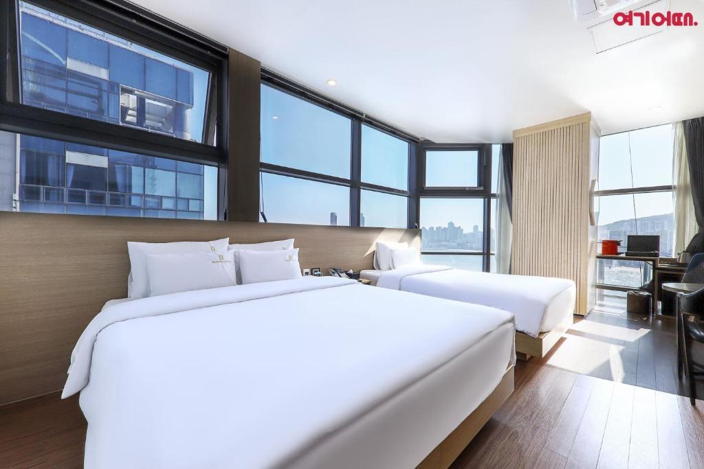 two beds in a hotel room with large windows at Gwanganri HOTEL OCEANVIEW in Busan