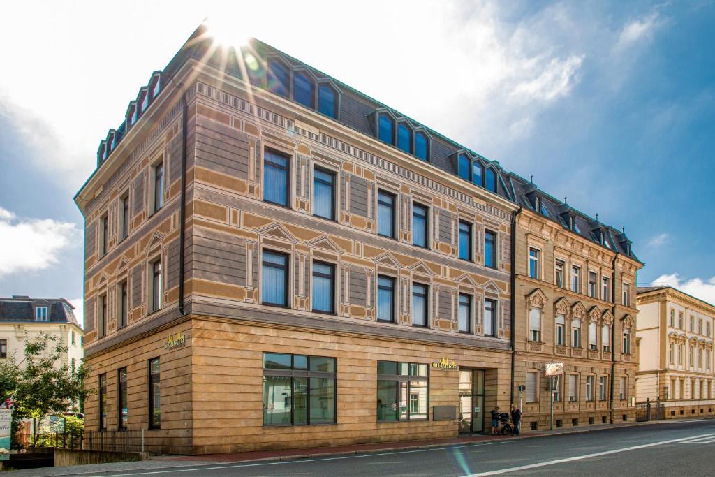 un gran edificio de ladrillo con el sol en el cielo en City Hotel Bamberg en Bamberg