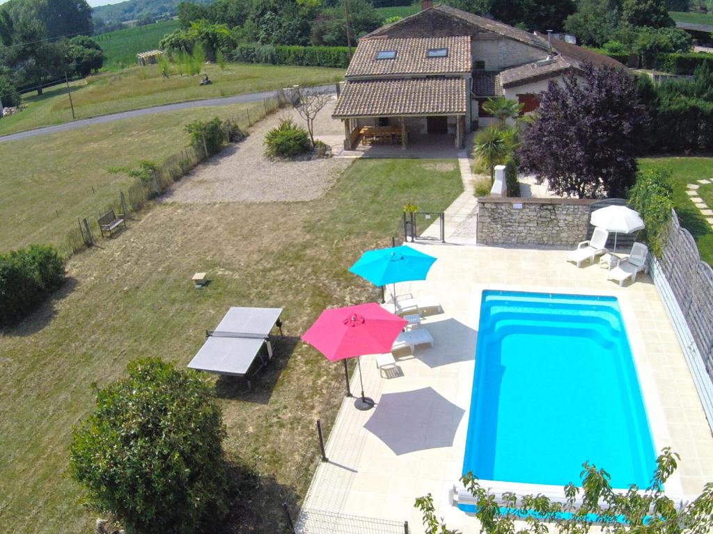an aerial view of a swimming pool with two umbrellas and tables at Gite les Fleurs in Eymet