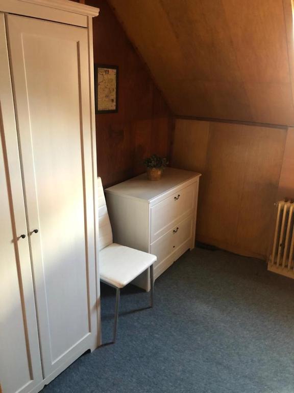 a small room with a white chair and a dresser at Turistická Chata Pláně in Český Dub