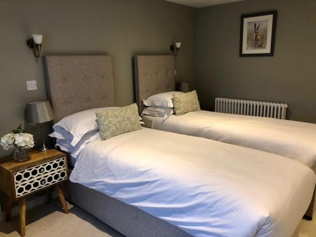 a bedroom with two beds and a table with a lamp at The Kings Head in Whiteparish