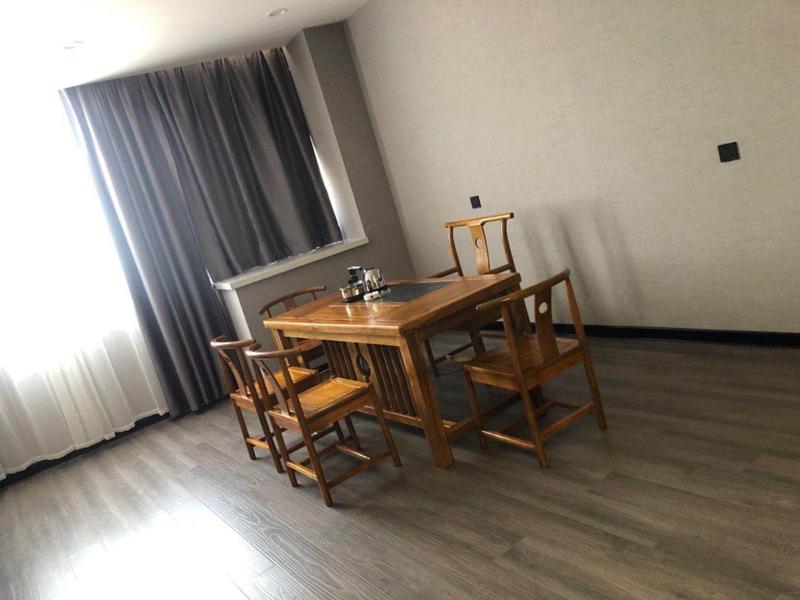 een houten tafel en stoelen in een kamer bij Thank Inn Chain Hotel Hebei Handan Ci County Xinshiji in Handan