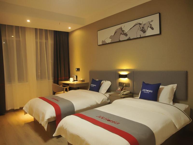 a hotel room with two beds and a desk at JUN Hotels Shandong Liaocheng Eco-Tech Development Zone Contmporary International Plaza in Liaocheng